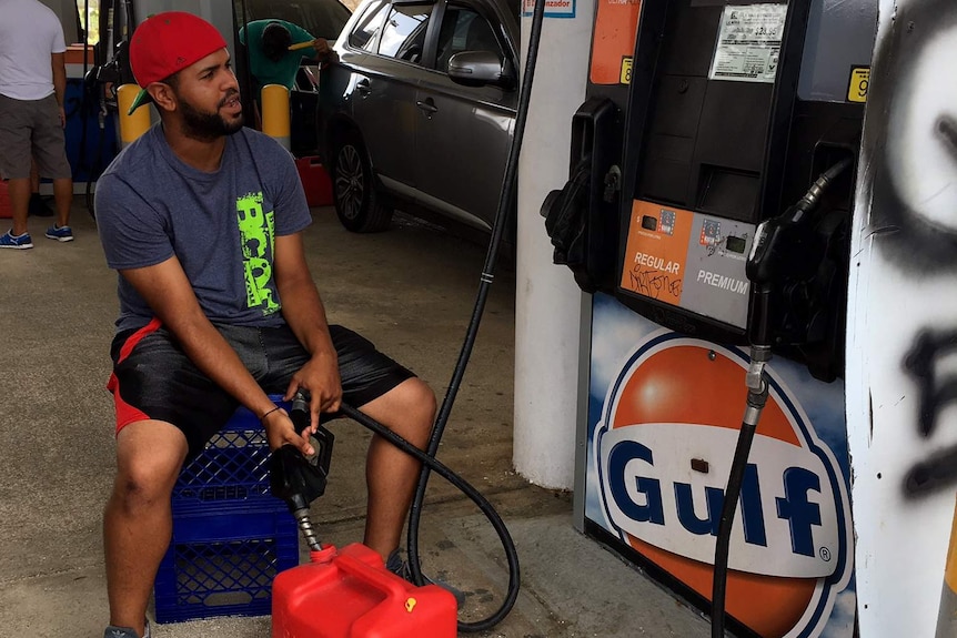 Man fills up a red container with petrol in Puerto Rico at a petrol station