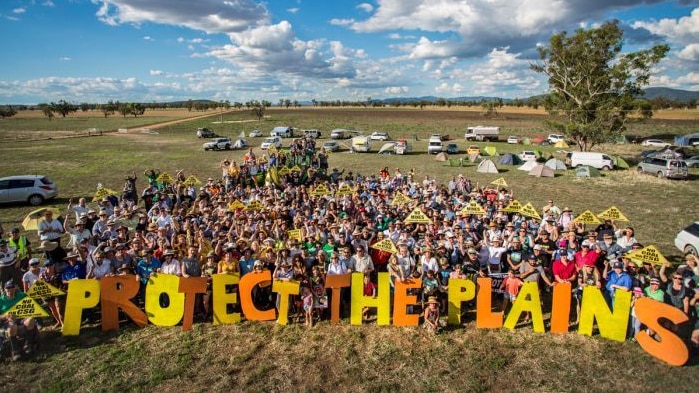 A group of people holding placards rally against a mine proposal.