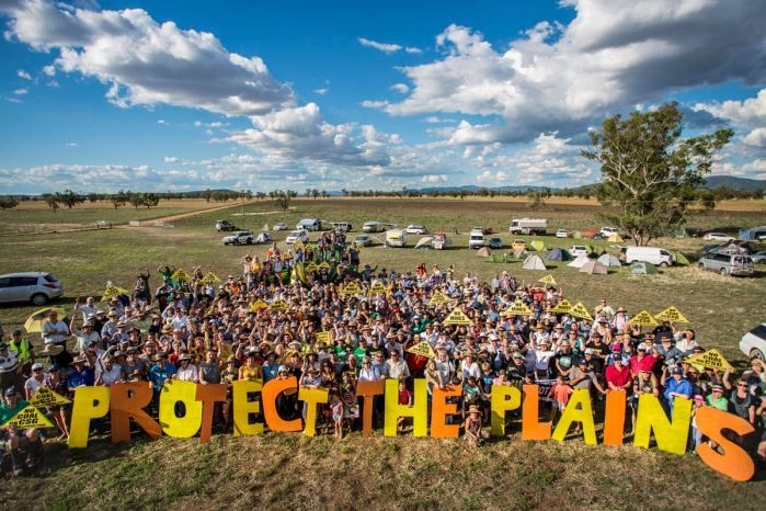 A group of people holding placards rally against a mine proposal.