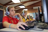 Primary school students wearing headphones and working on practice NAPLAN tests on their computers.
