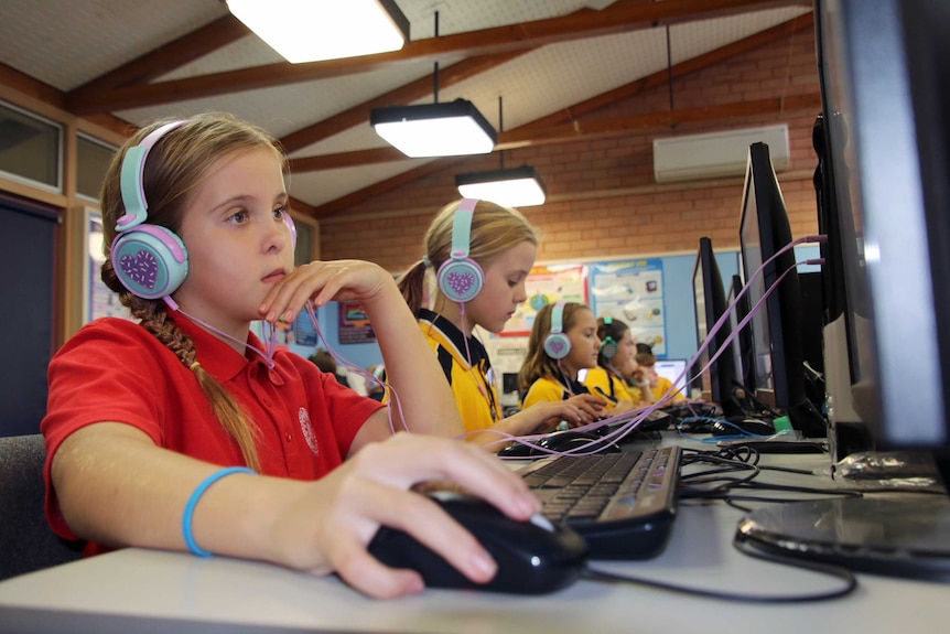 Primary school students wearing headphones and working on practice NAPLAN tests on their computers.