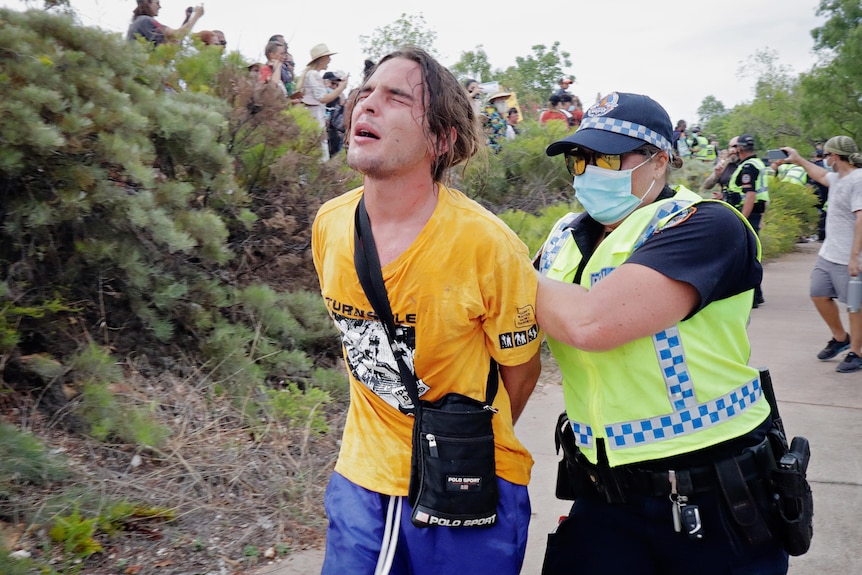 A boy is led away by a police officer