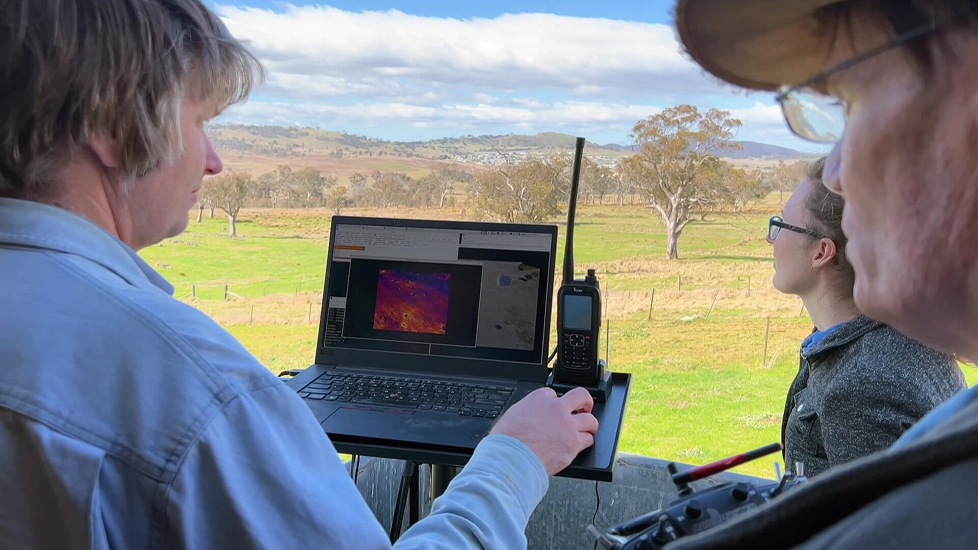 ANU researchers look at a screen that is being fed aerial vision of a scout drone used to map fires