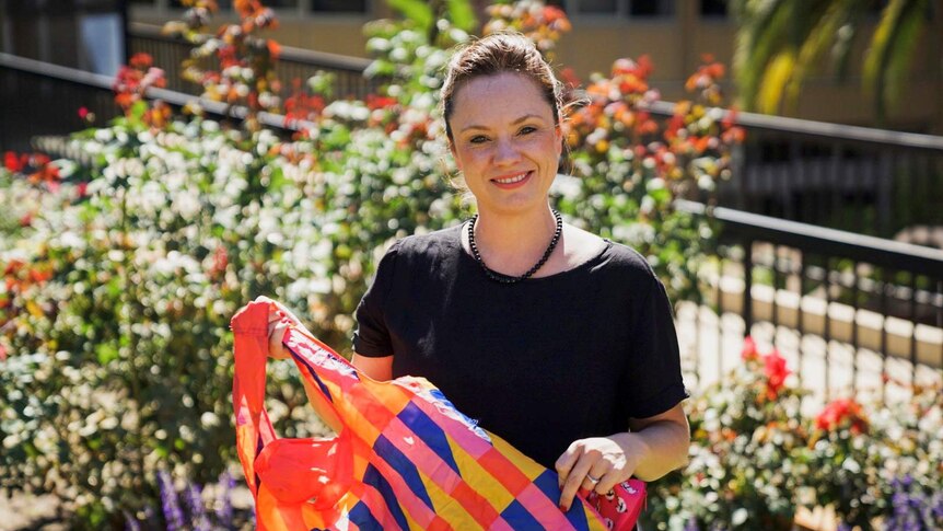Sarah Quinton holding a colourful reusable shopping bag.