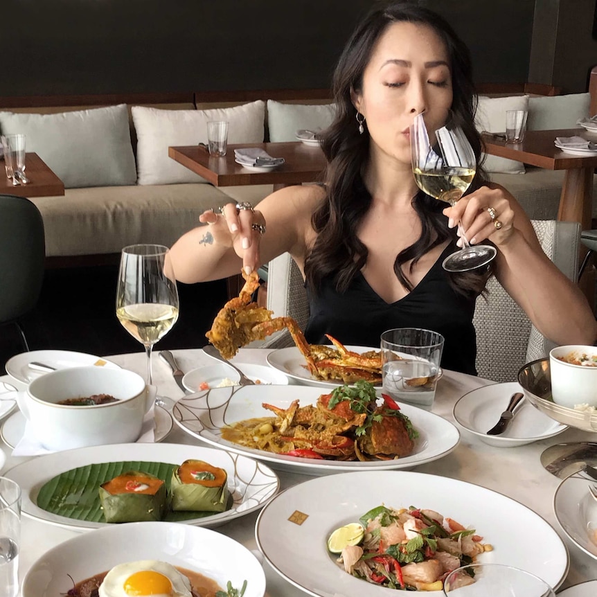Melissa Leong picks up a crab while sipping white white.