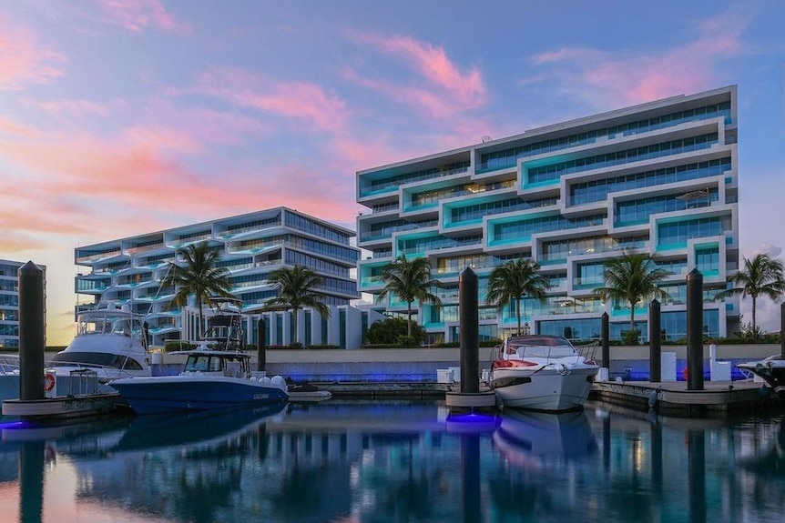 Two apartment buildings overlooking a marina at sunset 