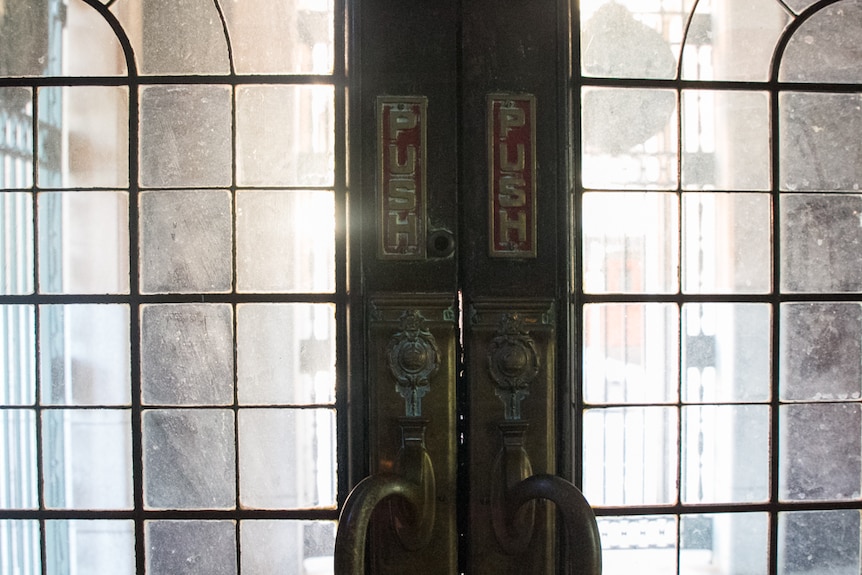 The original door handles and push signs on the glass doors at the side entrance off Elizabeth Street.