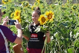 A girl holding sunflowers smiles for the photo getting taken