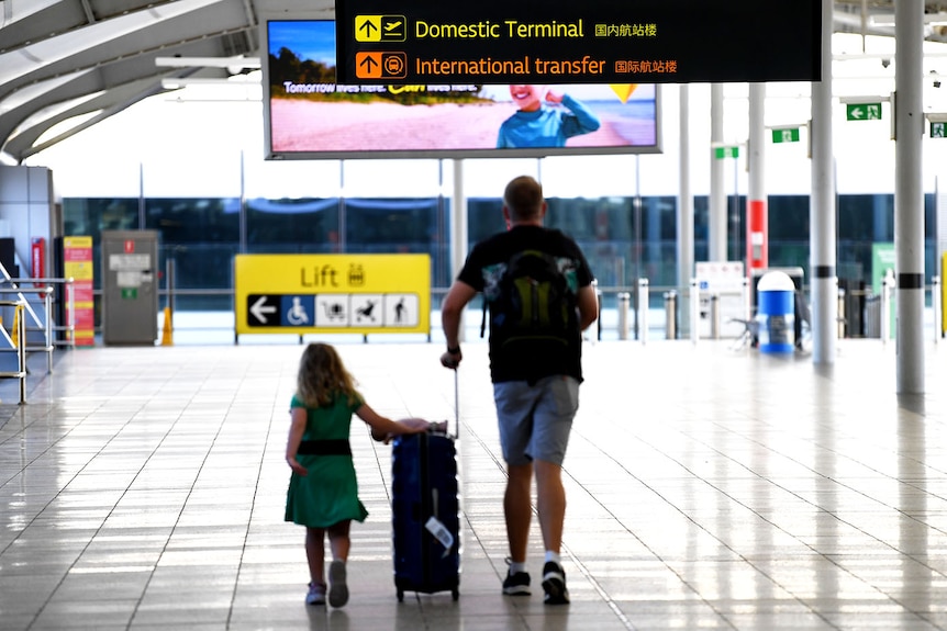 A man and his daughter walk with luggage at the domestic terminal in Brisbane airpor.