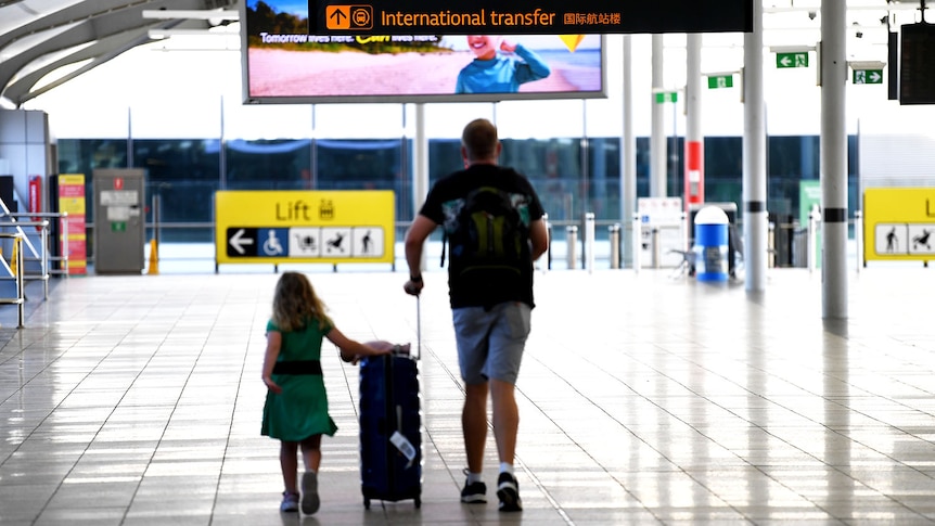 A man and his daughter walk with luggage at the domestic terminal in Brisbane airpor.