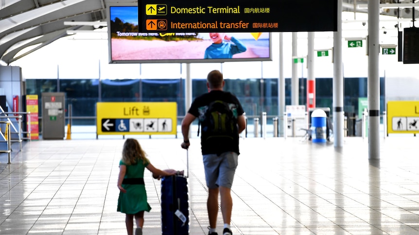 A man and his daughter walk with luggage at the domestic terminal in Brisbane airpor.