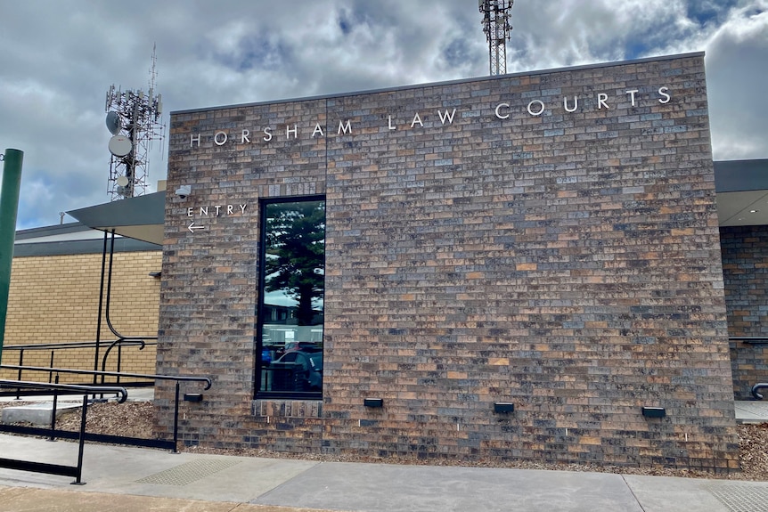 A dark brick building facade on a cloudy day. the words "Horsham Law Courts" and "Entry" are on the front