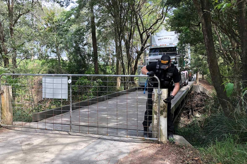 A security guard closing a gate to a road accessing a rural property