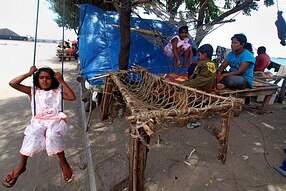 Sri Lankan migrant women and children relax next to their makeshift tents at the Indonesian port town of Merak on April 7, 20...
