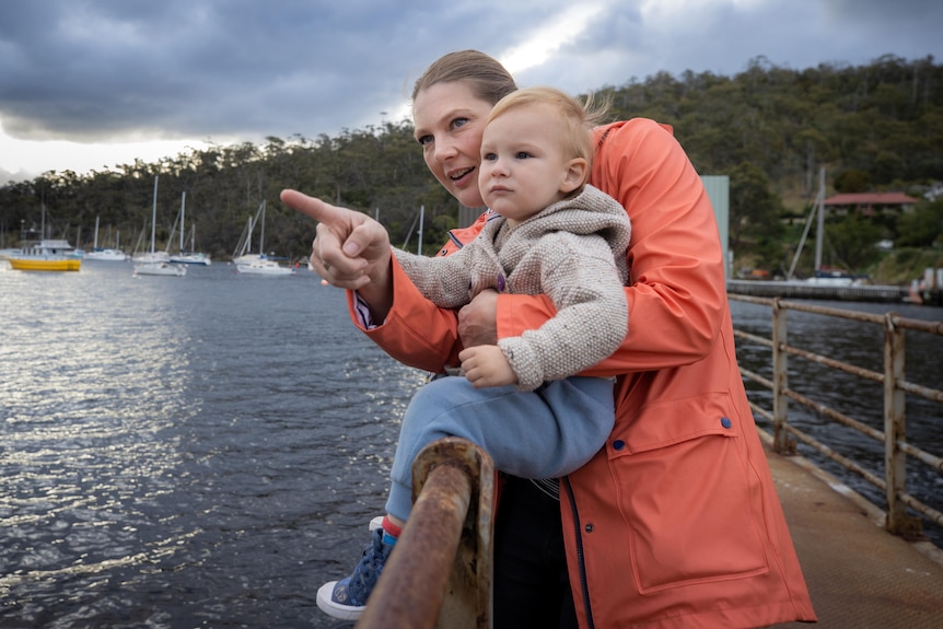 Woman with her young son sitting on a railing on a wharf.