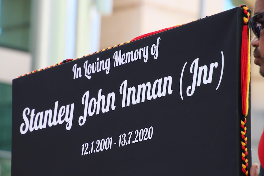 a black placard with white writing which reads "in loving memory of stanley john inman jnr"