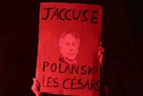 A woman holds a poster reading "I accuse Polanski, the Cesar" in French.