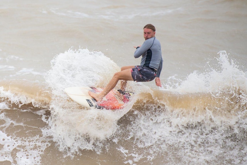 Man surfing in brown water.