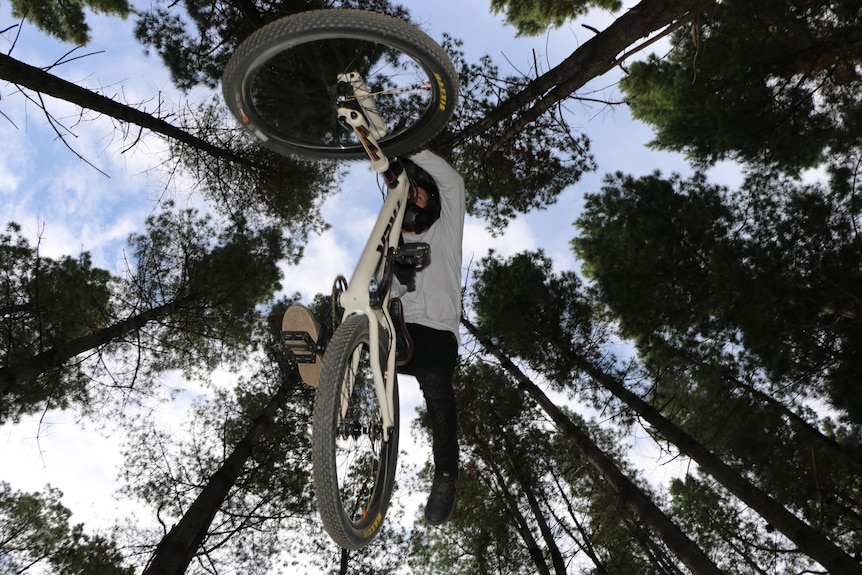 A man on a mountain bike jumps over the camera.