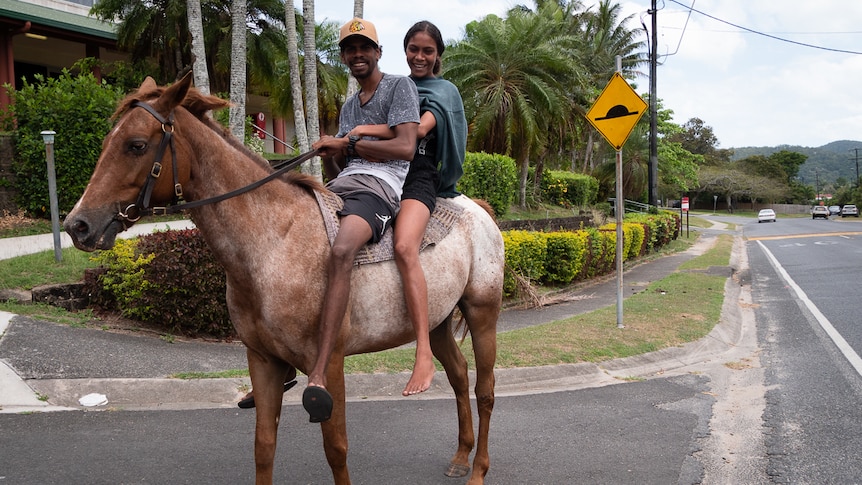 Two Aboriginal teens riding horse on community street