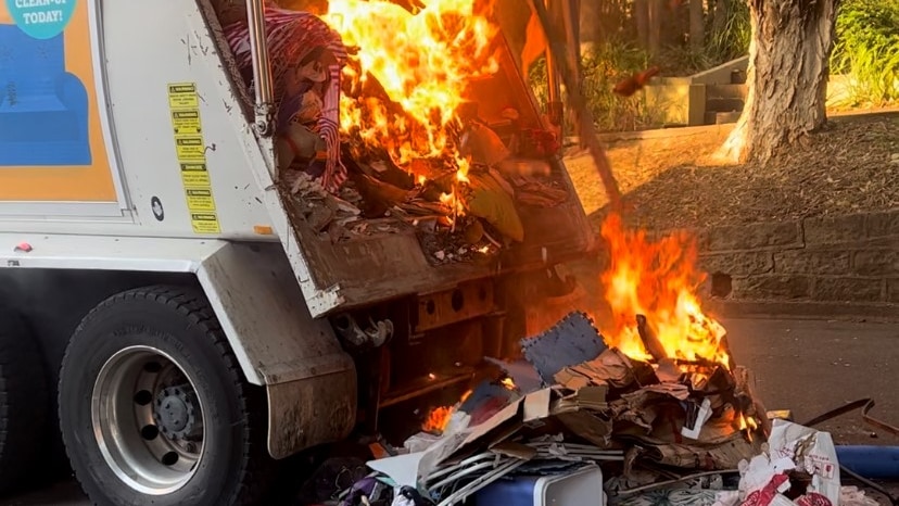 A ferocious fire burning in the back of a garbage truck.