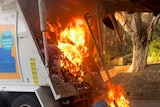 A ferocious fire burning in the back of a garbage truck.