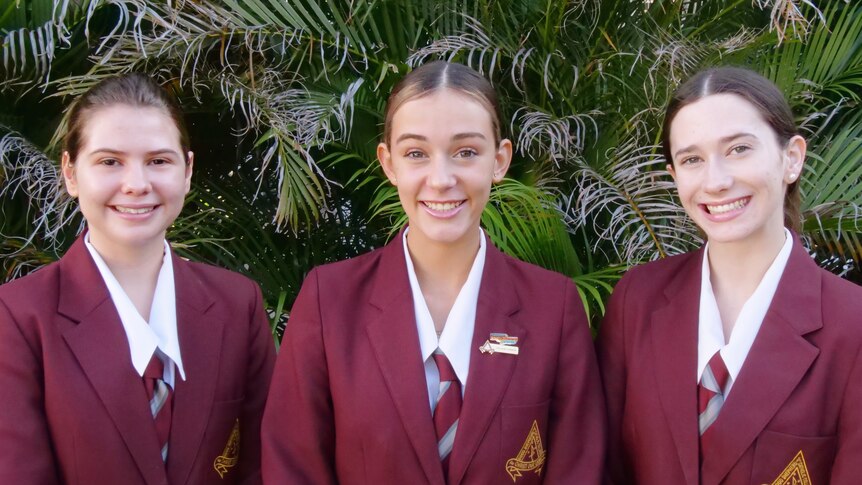 Three teenage schoolgirls in red uniforms.