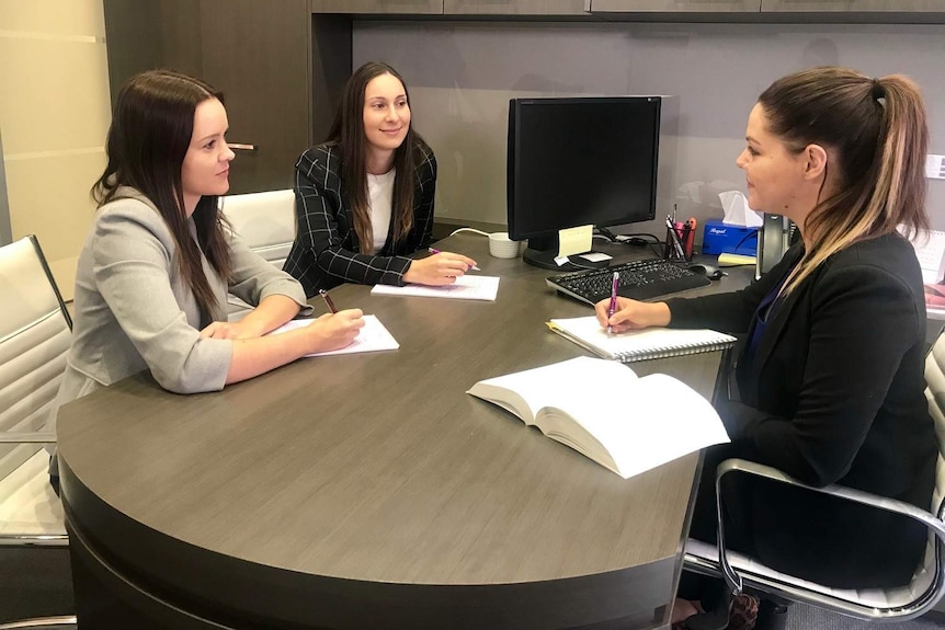 Three women in a law firm sitting at a desk.