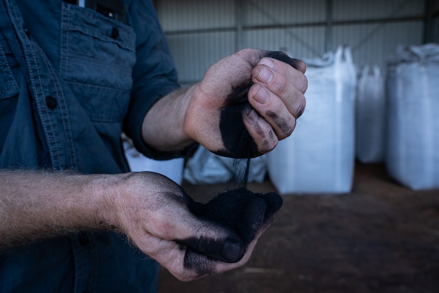 Refined coal dust being poured from one hand to the other.