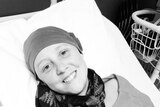 Connie Johnson in beanie and scarf laying on hospice bed.