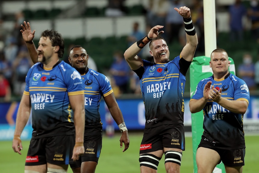 A number of Western Force players smile and wave to the crowd after a win
