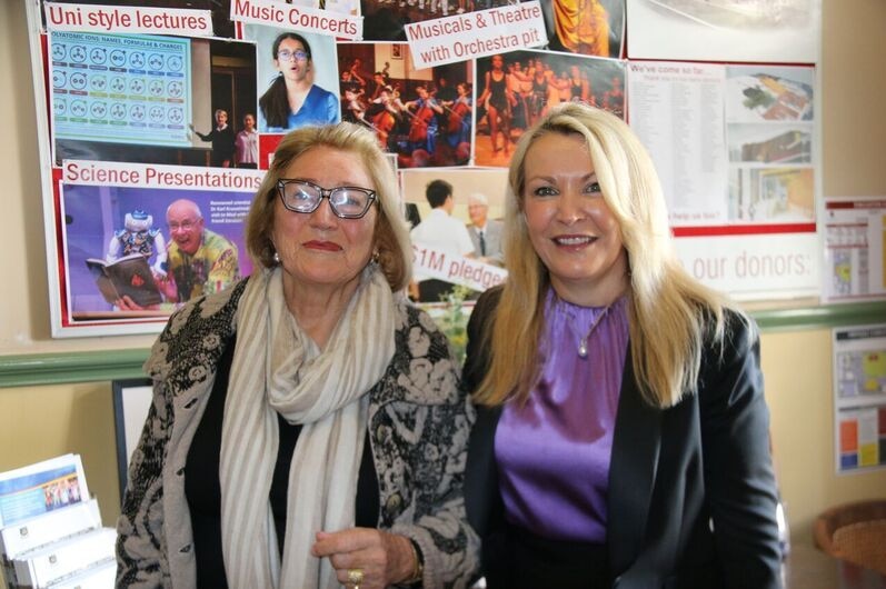 Two ladies sitting smiling at the camera.