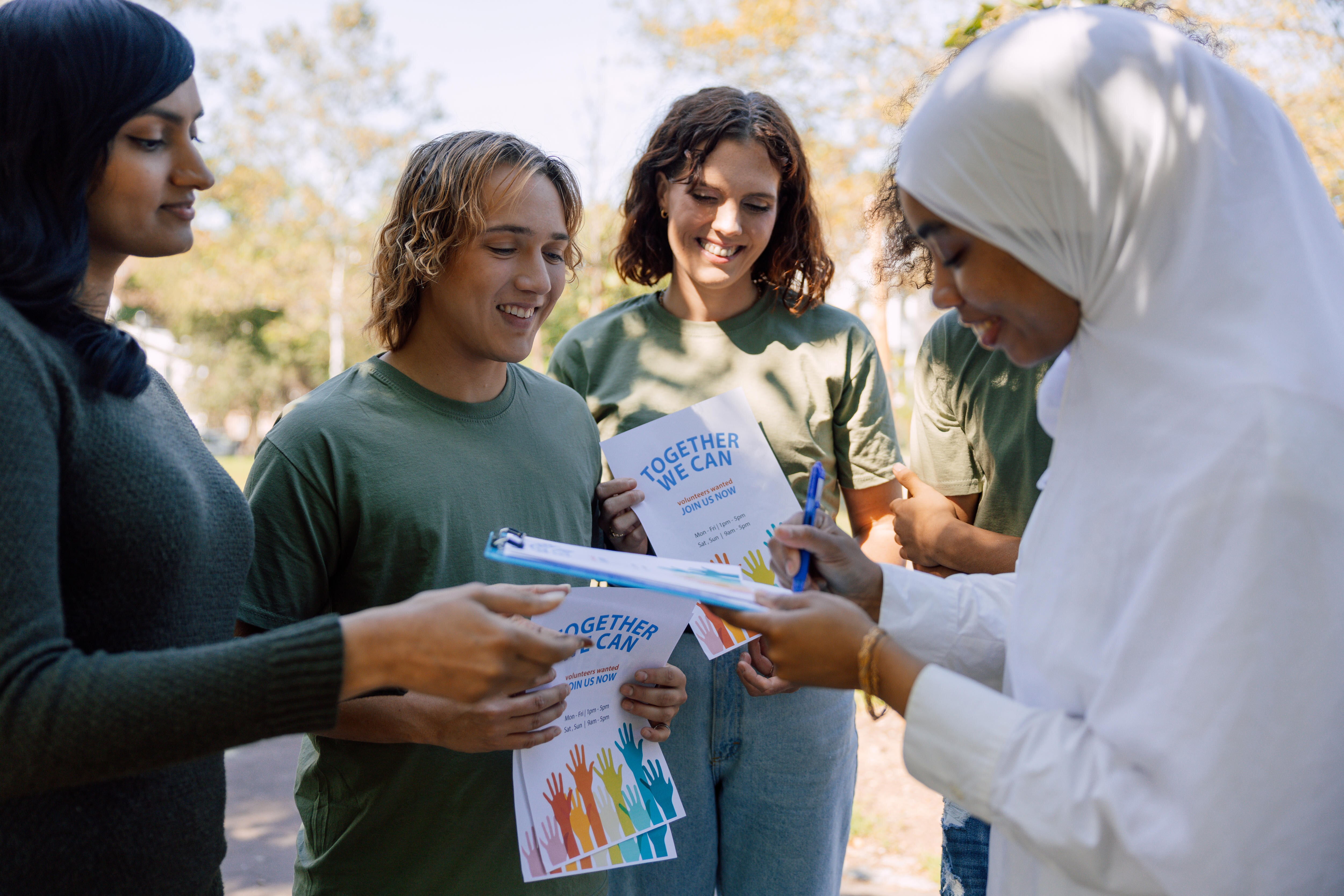 A group of young people stand around looking at a petition to sign.  