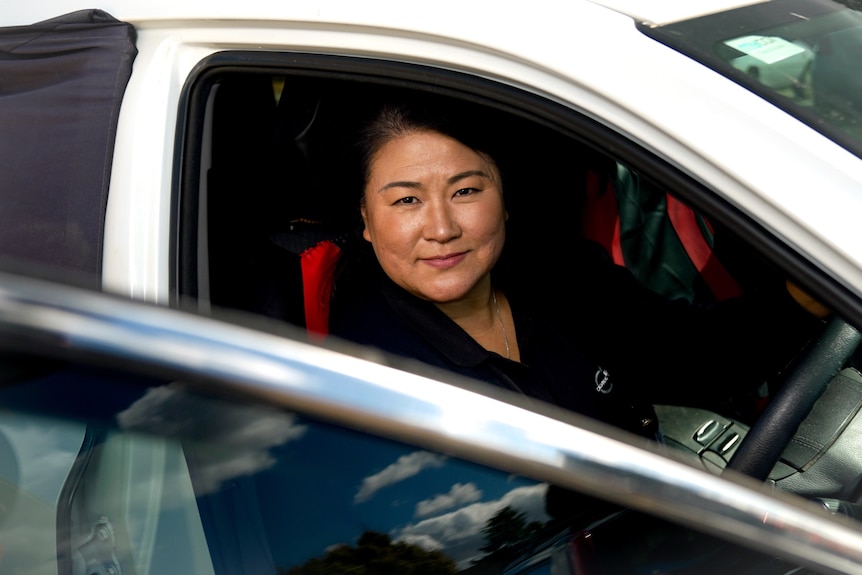 A woman sits in the driver's seat of a car.