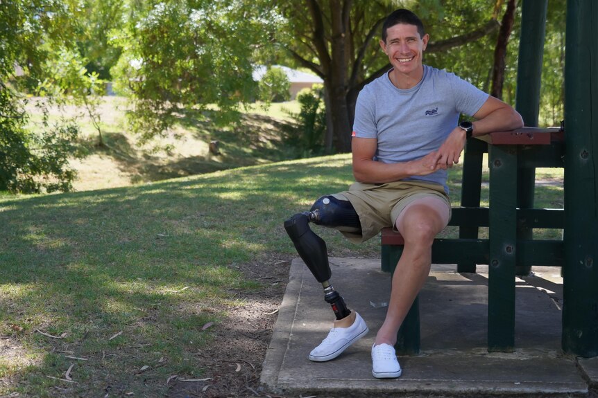 Amputee Darren Hicks sits at a park bench with his prosthetic leg