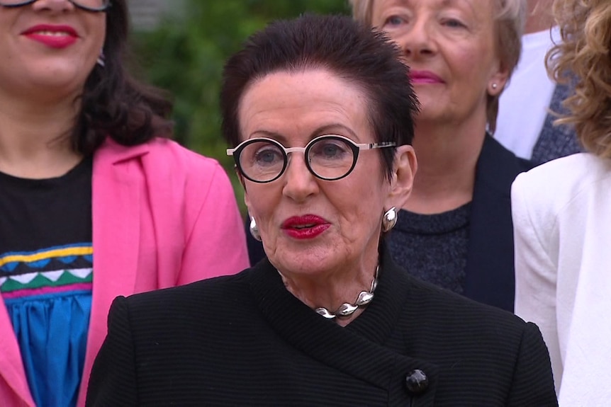 a woman wearing glasses speaking outdoors 