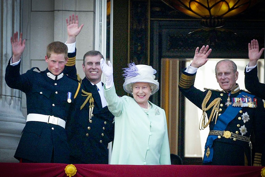 The Queen in a pale green outfit waves from a balcony, surrounded by Harry, Andrew and Philip