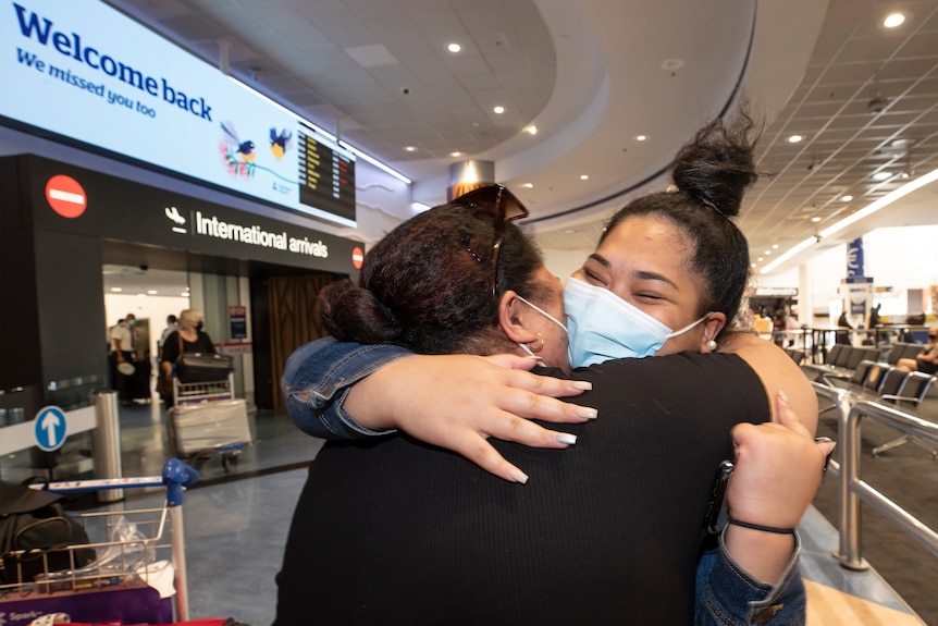 Two women embrace after one arrives on a flight from Australia at Auckland airport