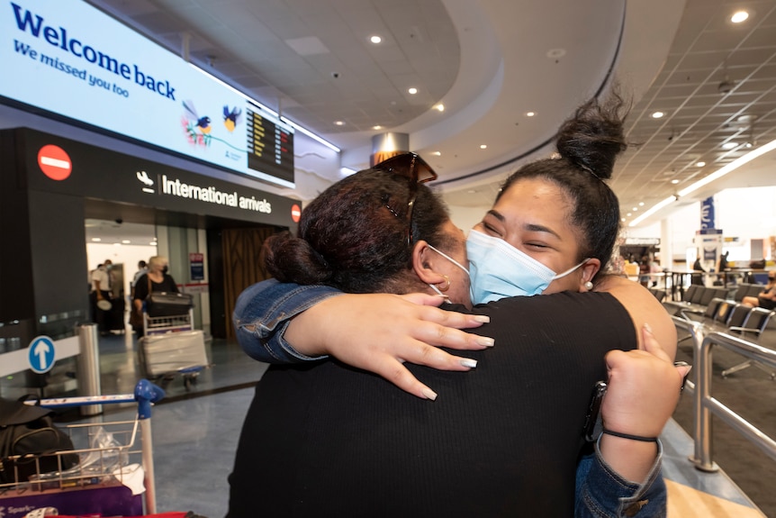 Deux femmes s'embrassent après l'arrivée de l'une d'elles sur un vol en provenance d'Australie à l'aéroport d'Auckland