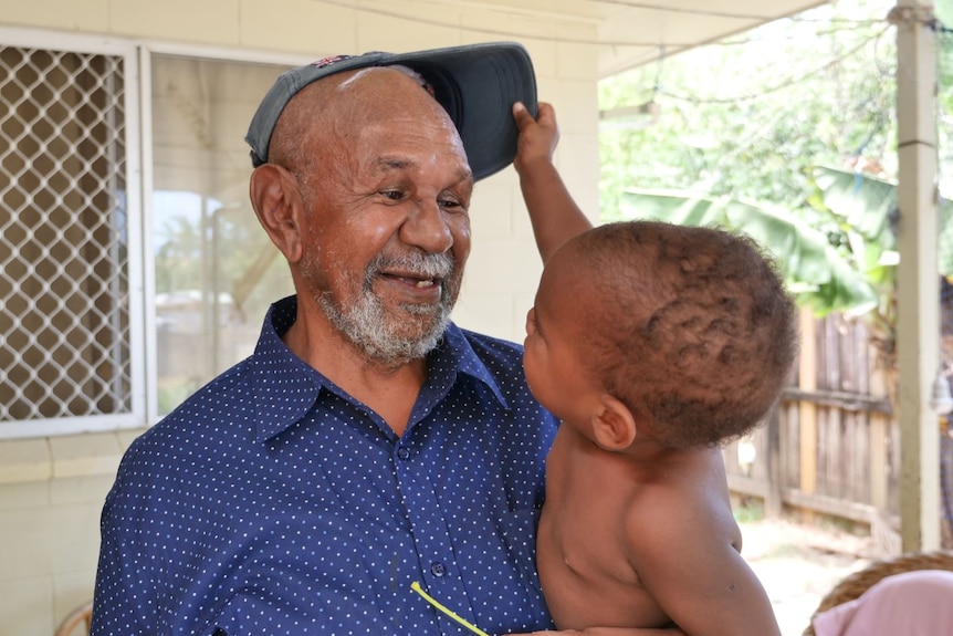Baby grabs hat off older Torres Strait Islander man's head