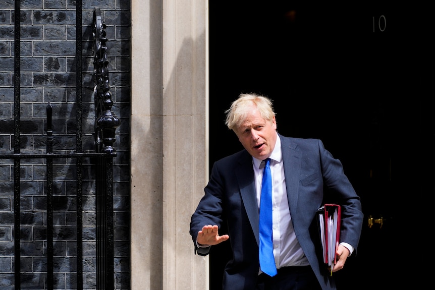 Boris Johnson gestures to journalists and photographers as he leaves 10 Downing Street