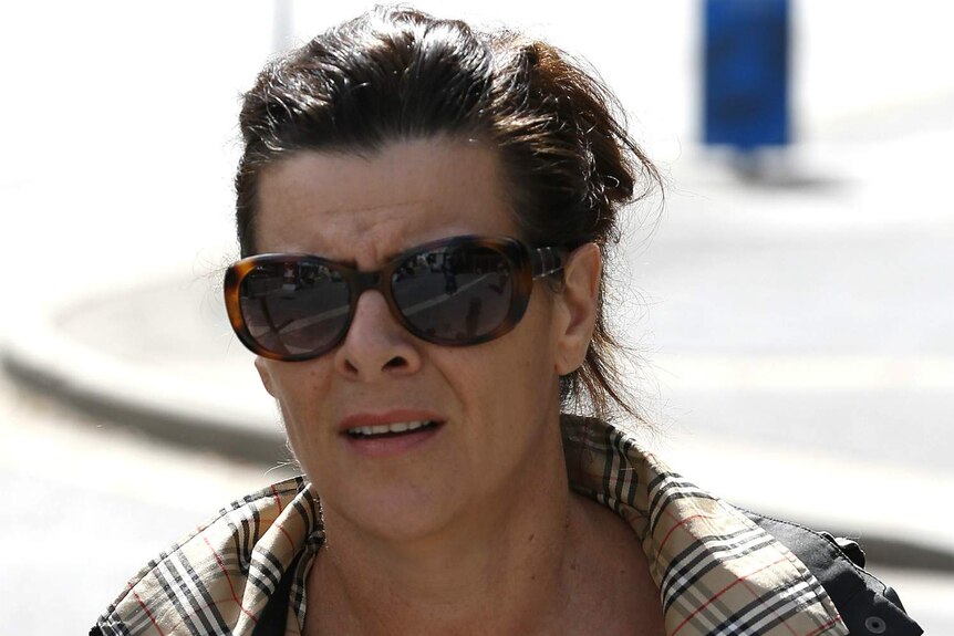 Linda Brooks, wearing sunglasses, walks to the court complex.