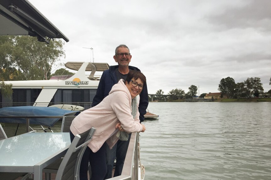 Joanne Seaton and Steve Kitto lean over the railing at the end of their houseboat moored on the River Murray at Berri.