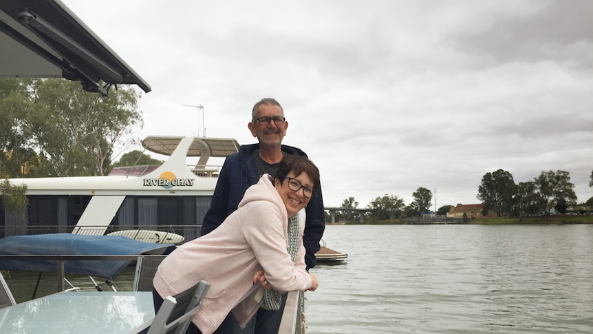 Joanne Seaton and Steve Kitto lean over the railing at the end of their houseboat moored on the River Murray at Berri.