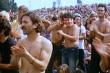 People clap in the muddy crowd of the Woodstock 1969 festival