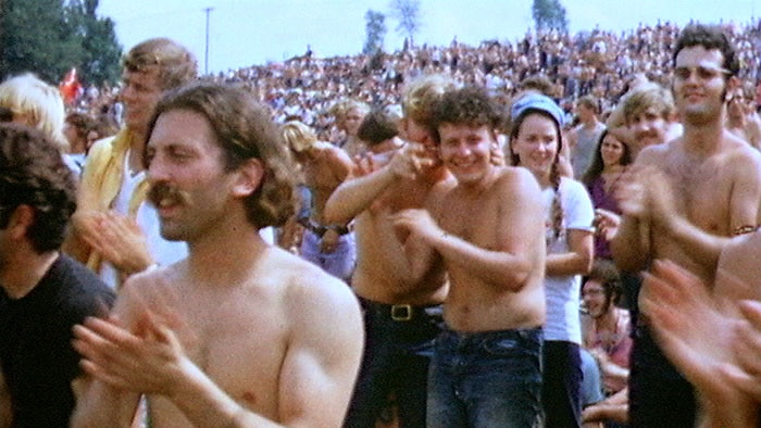 People clap in the muddy crowd of the Woodstock 1969 festival