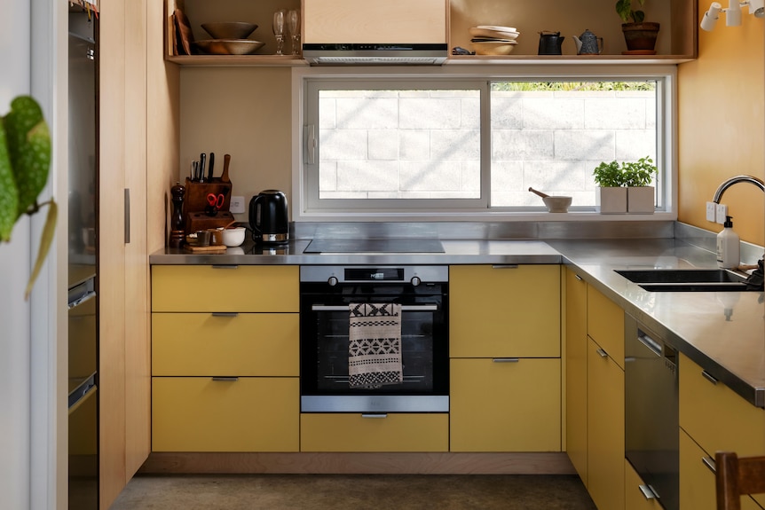 The kitchen is seen with simple, yellow and natural finishes. 