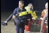 a rescue worker carries a woman who was pulled out of  floodwaters