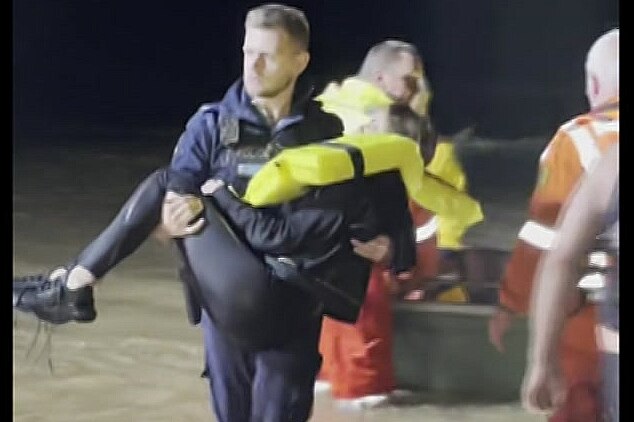 a rescue worker carries a woman who was pulled out of  floodwaters