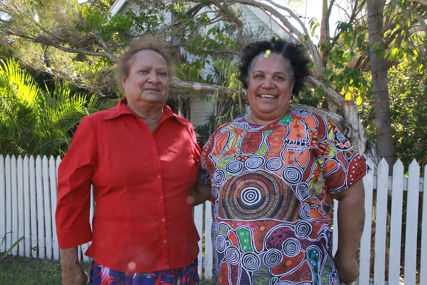 Aunty Sally Vea Vea in a red shirt and Kristina Hatfield in a colourful Aboriginal art shirt stand together.